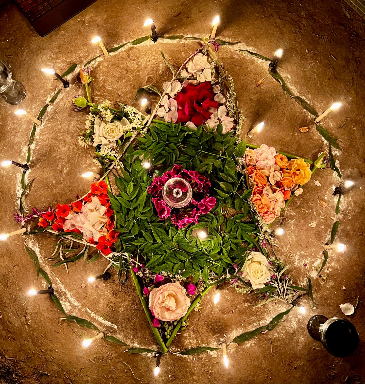 A six pointed star made of roses and plants. Candle work for the solstice using tallow candles.